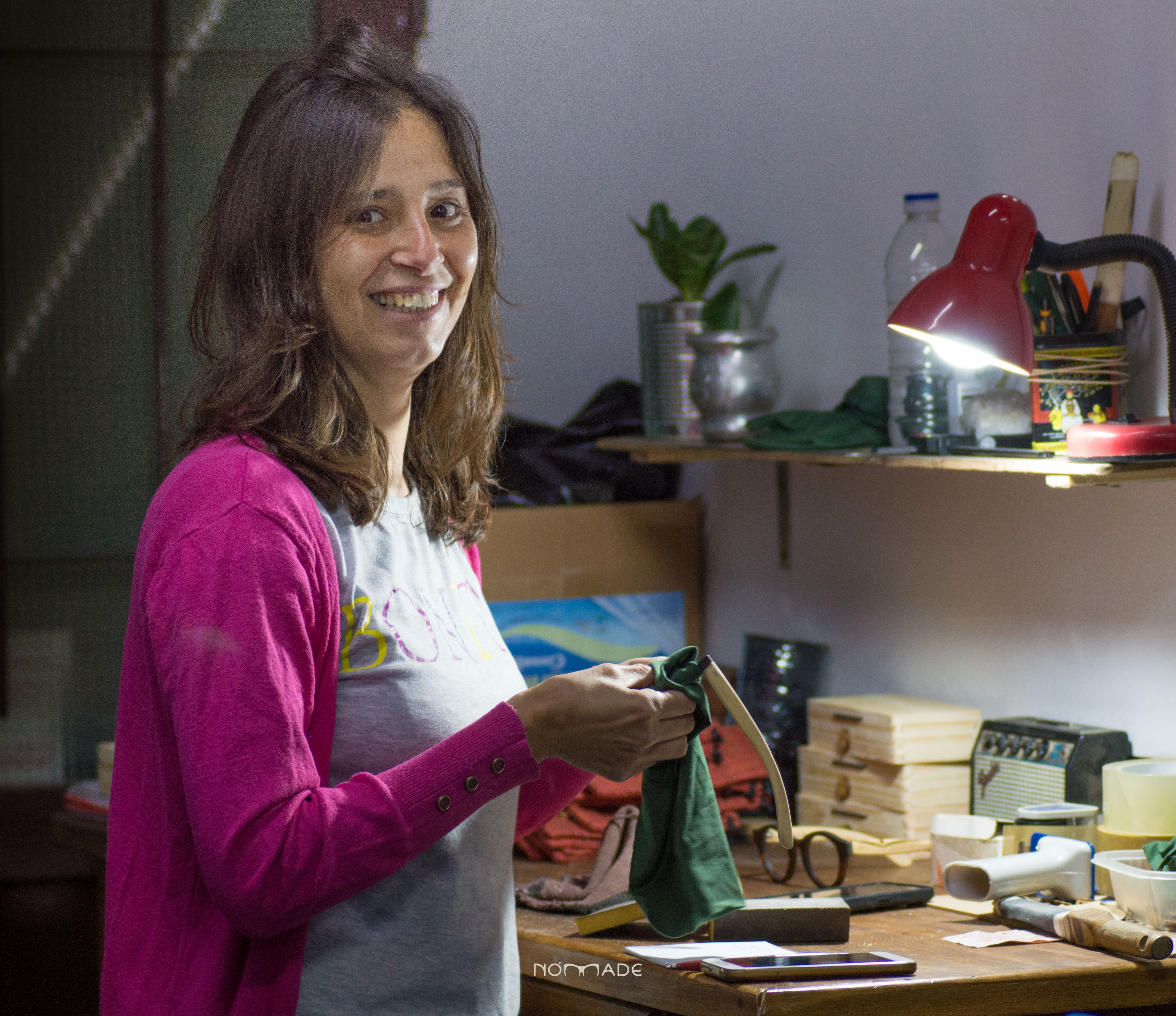 mujer de medio perfil sonriendo a la camara mientras trabaja con anteojos de madera
