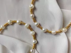 Pulseiras douradas e pérolas naturais