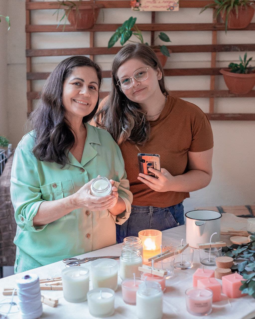 a imagem mostra a mãe, Rosalda e a filha Diana, a mãe está segurando uma vela e a filha o celular.