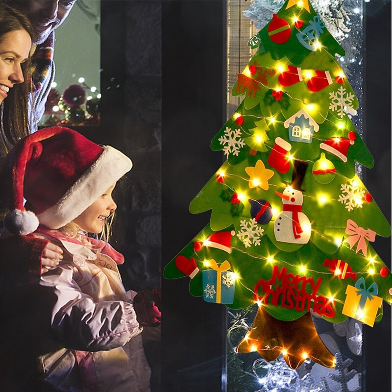 Pai, mãe e filha olhando para a árvore de natal em feltro montessori com pisca pisca