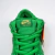 O tênis Nike Dunk Low SB St. Patrick's Day é um modelo masculino com um visual marcante, sendo predominantemente verde com detalhes em dourado no swoosh. O material é uma combinação de camurça e tecido, e o tipo de ajuste é por cadarços. Este modelo está 