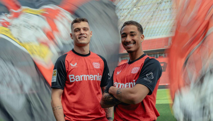 camisa titular do Bayer Leverkusen 2024-2025 da Castore em vermelho vibrante com detalhes em preto. A camisa apresenta gráficos sutis que homenageiam a cidade de Leverkusen, incluindo diamantes inspirados na torre d'água, cruzes que remetem ao brasão de armas e o mapa da cidade em si. 