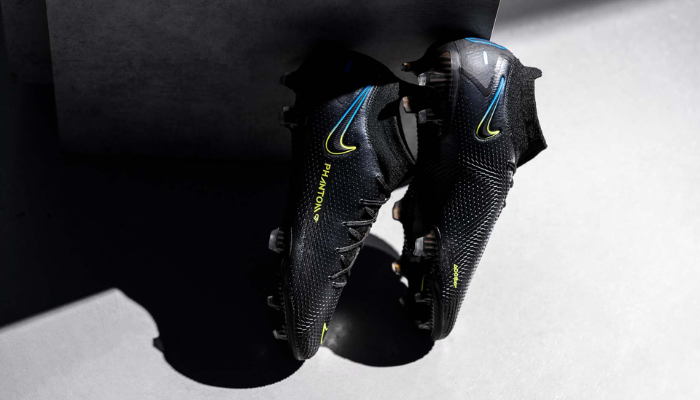 Chuteira de futebol Nike Phantom GT Elite FG Black Prism, exibindo um design moderno e tecnológico. A parte superior em Flyknit apresenta uma textura aderente, ideal para um toque preciso na bola. A sola possui tração especializada para movimentos ágeis e controle em campo. 