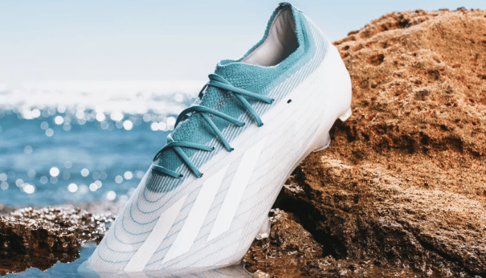 chuteira de campo Adidas X Speedportal.1 FG Parley da adidas Football x Parley. A chuteira é predominantemente branca com detalhes em azul que lembram o oceano. Possui uma placa de fibra de carbono no calcanhar para impulsos explosivos, travas multidirecionais para tração e estabilidade, sistema de estabilidade de alta velocidade para suporte, cabedal SpeedSkin leve e adaptável com grip para melhor controle da bola e um collar Primeknit que trava o pé firmemente dentro da chuteira.