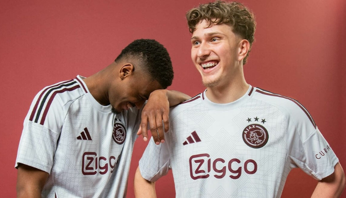 nova terceira camisa do Ajax para a temporada 2024-2025. A camisa é predominantemente branca, com detalhes em cinza e bordô. O design é inspirado na Escola de Amsterdã e apresenta linhas gráficas, gola redonda com friso bordô, três listras da Adidas em bordô e preto, escudo do Ajax e logo da Adidas em bordô, arcos laterais em bordô e cruzes de Santo André na nuca.