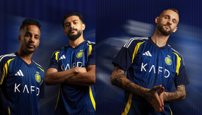 camisa reserva oficial do time de futebol Al-Nassr para a temporada 2024/2025, produzida pela Adidas. A camisa apresenta um design moderno e elegante, com as cores azul marinho, azul royal, amarelo e branco. 