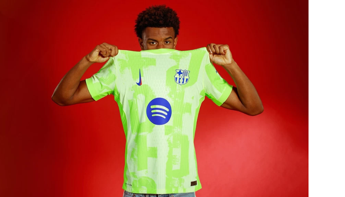 nova terceira camisa do Barcelona para a temporada 2024/25. A camisa é predominantemente verde, com detalhes em azul e vermelho. O escudo do Barcelona, em uma versão especial, e o Swoosh da Nike em azul com detalhe vermelho se destacam no design. 