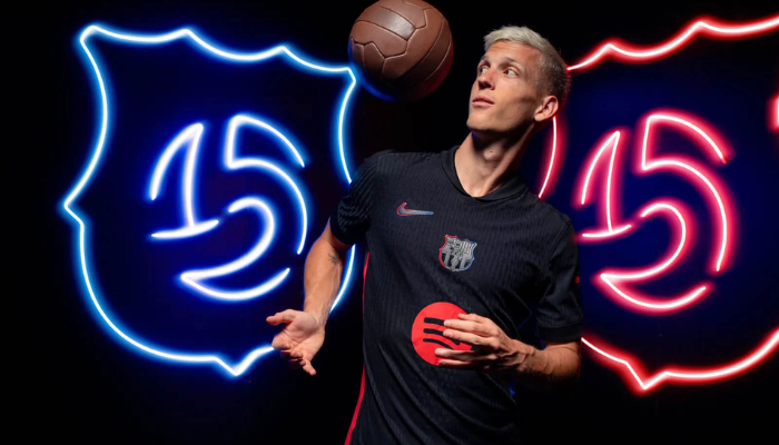 Camisa reserva do Barcelona 2024-2025 da Nike. A peça apresenta a cor preta como predominante, com o escudo do clube aplicado em TPU com efeito brilhante no centro. O Swoosh da Nike aparece com contorno degradê azul e vermelho. A gola é estilo "mini-polo" e as laterais possuem as cores clássicas do Barcelona. Na nuca, a bandeira da Catalunha.