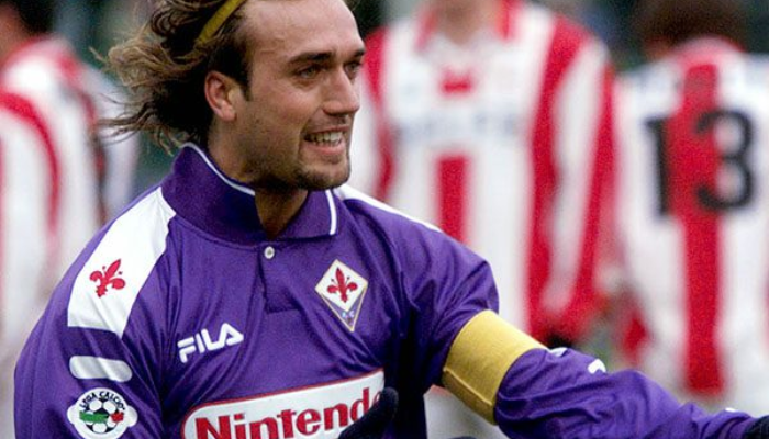 Camisa retrô titular da Fiorentina Fila da temporada 1998-1999, com as cores roxa e branca. A camisa exibe o logo da Fila e o número 9, em referência ao lendário Batistuta. A imagem captura a essência da época de ouro da Viola, com Trapattoni como técnico e a equipe brigando por títulos importantes.