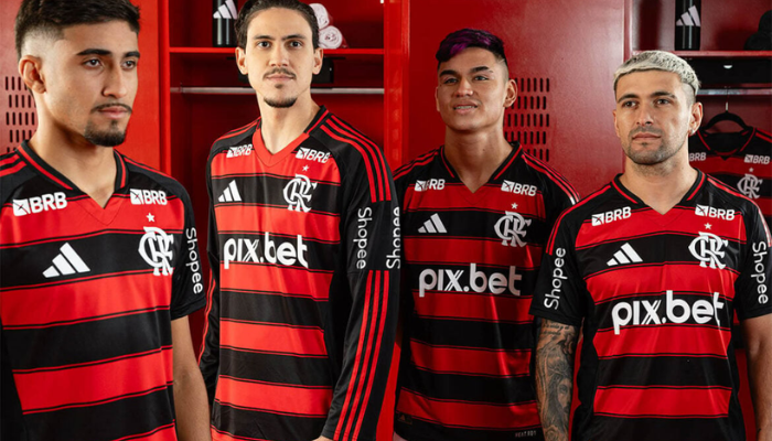 Camisa Flamengo Titular Adidas 2025/26, modelo rubro-negro com listras horizontais e detalhes em branco. Gola V preta com friso vermelho na versão jogador e corte V padrão vermelho na versão torcedor. Ombros pretos com três listras vermelhas da Adidas. Escudo CRF e logo Adidas em branco no peito, numeração e patrocínios em branco nas costas.