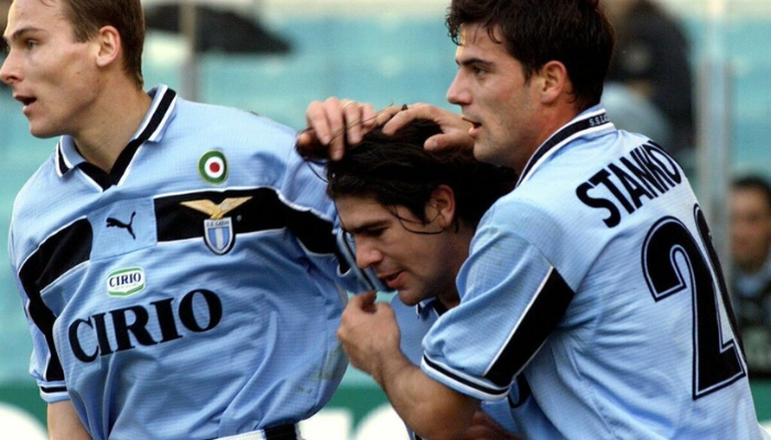 A camisa titular retrô da Lazio da temporada 99/00, em azul celeste e preta, exibe o logo da Puma e o escudo do clube. Este modelo histórico foi utilizado durante a celebração do centenário da Lazio e na conquista da Copa das Copas, com a vitória sobre o Mallorca na final.