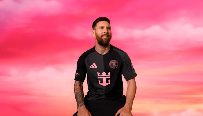 A camisa reserva do Inter Miami CF para 2025, a Fortitude, apresenta um design inovador com a divisão em preto e cinza escuro, detalhes em rosa vibrante e os logotipos da Adidas e do clube em destaque.