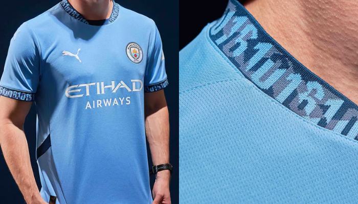 Camisa titular do Manchester City para a temporada 2024/25. A camisa é predominantemente azul celeste com gola e punhos em azul escuro. Na gola e nos punhos, há um gráfico exclusivo com o código de área 0161 de Manchester. O escudo do Manchester City está no lado esquerdo do peito, enquanto o logotipo da PUMA e o patrocinador da Etihad estão no lado direito.