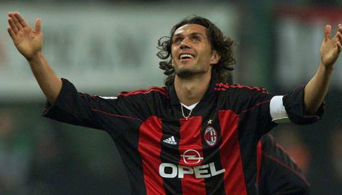 camisa titular Adidas do AC Milan da temporada 2000-01. A camisa apresenta listras pretas e vermelhas vibrantes, gola em V branca e detalhes em dourado. O escudo do Milan está bordado no lado esquerdo do peito, enquanto o logotipo da Adidas está bordado no lado direito. 