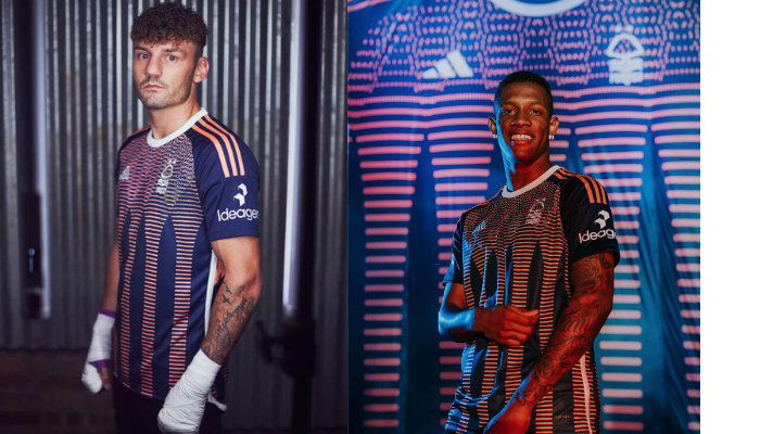 A imagem mostra a terceira camisa do Nottingham Forest da Adidas para a temporada 2023-2024. A camisa é predominantemente azul marinho, com gráficos em salmão na parte frontal inspirados no castelo de Nottingham.