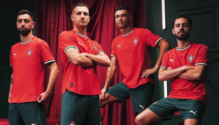 Camisa da Seleção Portuguesa 2025/26, fabricada pela Puma. Predominantemente vermelha, com detalhes em verde e branco, traz um design que homenageia os cinco besantes do brasão português. Inclui escudo da seleção, logo da Puma e detalhes históricos, como a quina no interior da gola.