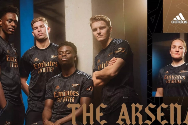 Camisa Reserva Arsenal Adidas 2022/23 em preto e dourado com gráfico 3D 'AFC', canhão dourado, listras cinza escuro nos ombros e patrocínios da Emirates e Visit Rwanda. Estilo exclusivo para torcedores apaixonados.