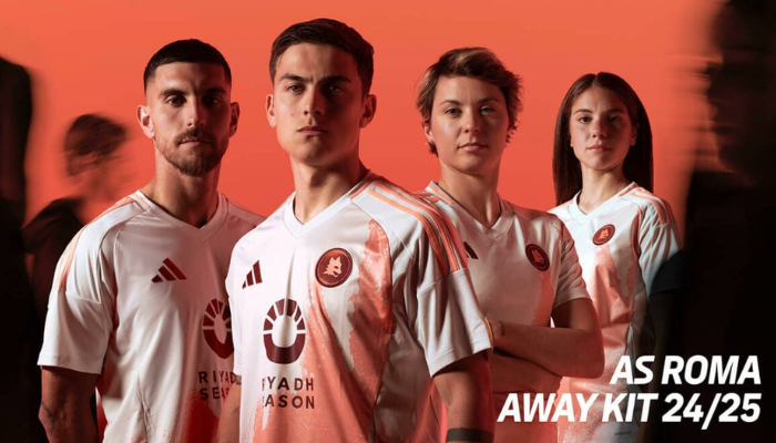 camisa reserva da AS Roma para a temporada 2024-2025. A peça, predominantemente off-white, possui um design inovador com um grande "manchado" laranja na parte frontal, inspirado nas artes urbanas romanas. Detalhes em bordô, como o logo da Adidas e o Lupetto, complementam o visual. 