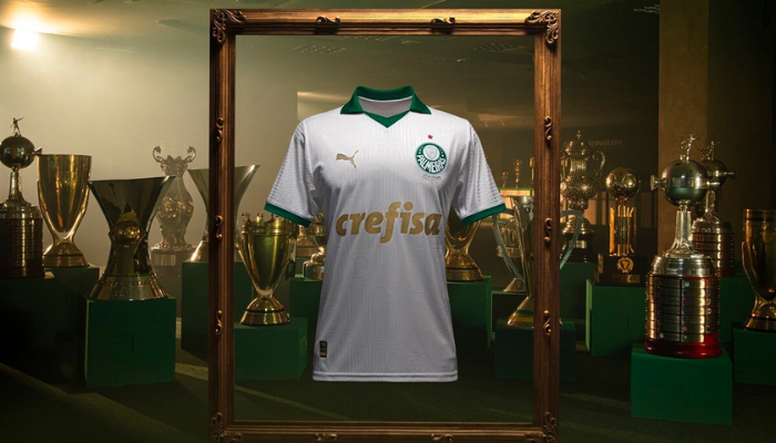 Camisa reserva Palmeiras Puma 2024-2025, modelo branco com gola pólo e punhos verdes, com detalhes dourados nos logos da Puma e Crefisa. O escudo do Palmeiras está no lado esquerdo do peito. 