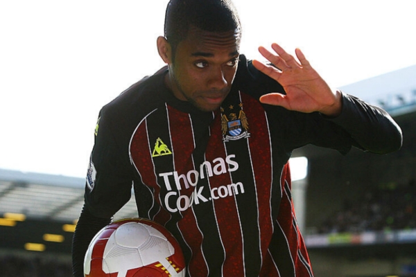 Camisa Retrô Manchester City Le Coq Sportif 2008/09 em azul manrinho, vermelha, branca e amarela, homenageando a temporada histórica com destaque para Robinho na Premier League e a participação emocionante na UEFA Cup.