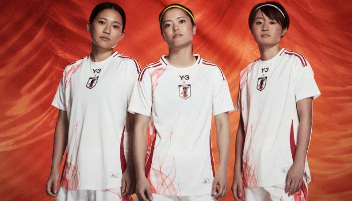 Camisa reserva da Seleção Japonesa para a temporada 2024-2025, em branco com detalhes em vermelho vivo. A camisa apresenta um design assimétrico exclusivo de Yohji Yamamoto, com chamas estilizadas que representam o estilo de jogo vibrante da equipe. 