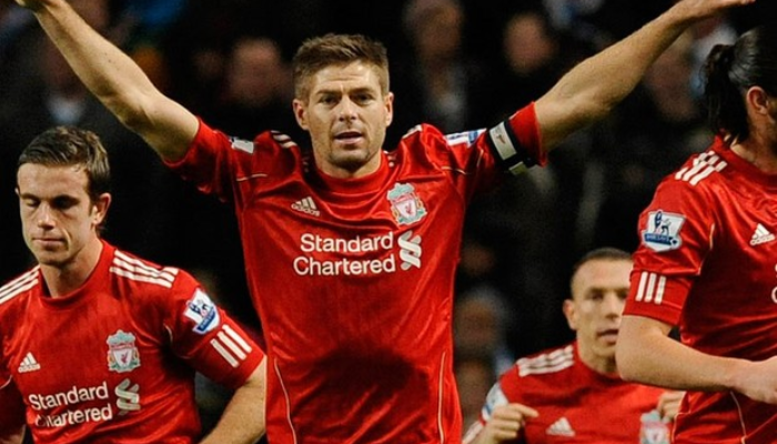 Camisa Retro Titular do Liverpool 2010-2012 em vermelho e branco. Camisa oficial usada durante a temporada turbulenta após a saída de Rafa Benítez e a chegada de Roy Hodgson. A equipe se recuperou com a volta de Kenny Dalglish e a contratação de Luis Suárez, conquistando a Copa da Liga.