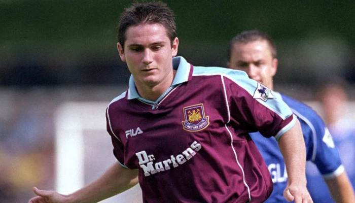 A camisa titular do West Ham United da temporada 1999-2000, produzida pela Fila, em um design clássico grená e azul. A imagem mostra a camisa com detalhes da época, incluindo o logo da Fila e o escudo do clube.