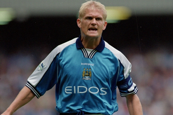 Camisa Retrô Manchester City 1999/01 em azul celeste com detalhes brancos, destacando o emblema do clube. Uma homenagem à temporada de 1999-2001, marcada pela ascensão do clube na Football League First Division.