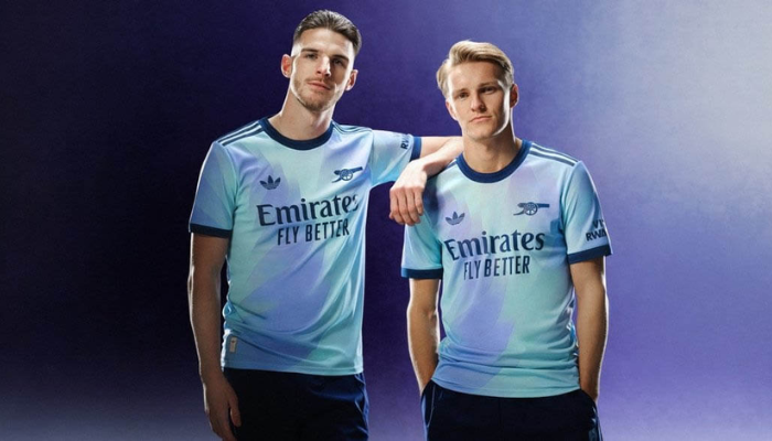 nova terceira camisa do Arsenal para a temporada 2024/2025. A camisa possui um design único com um degradê de azul claro para lilás, criando um efeito líquido. A gola é redonda e em azul petróleo, assim como as três listras da Adidas e o patrocínio. 