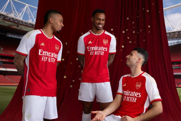 Camisa titular do Arsenal 2023/24 Adidas, vermelha e branca com detalhes dourados. Raios dourados, homenagem à invencibilidade 2003-2004. Gola redonda, três listras nas mangas.