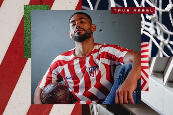 Camisa Titular Atlético de Madrid Nike 2022-2023 inspirada no rio Manzanares, com listras vermelhas e brancas, escudo Atleti no lado esquerdo e Swoosh Nike azul royal no lado direito.