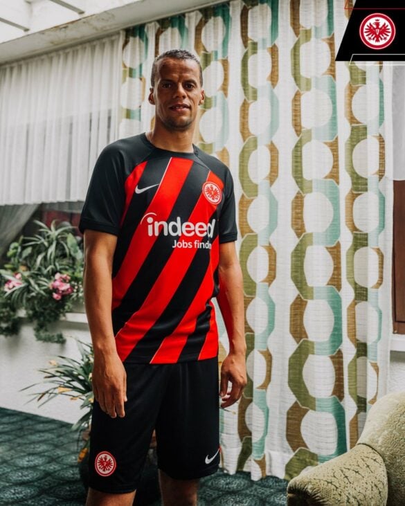 Camisa titular Eintracht Frankfurt Temporada 2023/24 Masculina Com faixas vermelhas e pretas diagonais ao longo do corpo, esta camisa é uma verdadeira homenagem à história do clube. A gola, ombros, mangas e punhos são pretos, enquanto o escudo do clube e o logotipo da Nike são exibidos em branco | Tevo Sports