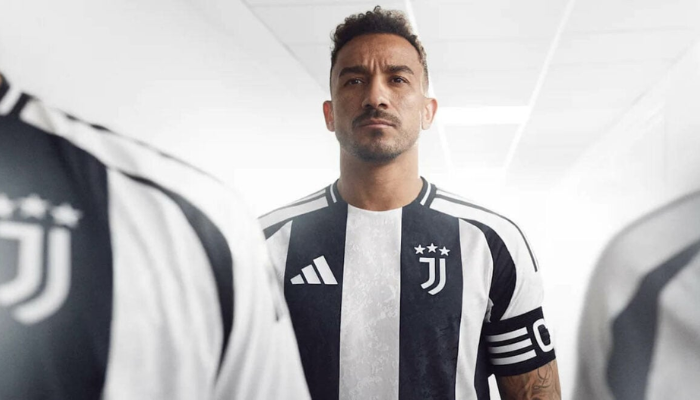 Camisa titular da Juventus para a temporada 2024-2025. A camisa branca apresenta listras verticais pretas com textura gráfica inspirada nas crateras da lua. Gola redonda preta com friso central branco, ombros brancos com painéis laterais pretos e arcos brancos nas laterais.