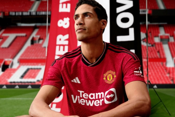 Camisa titular do Manchester United Adidas 2023/24 em vermelho vibrante, destacando padrão gráfico de rosas, listras elegantes e inspiração na rosa de Lancashire e na ponte Irwell.