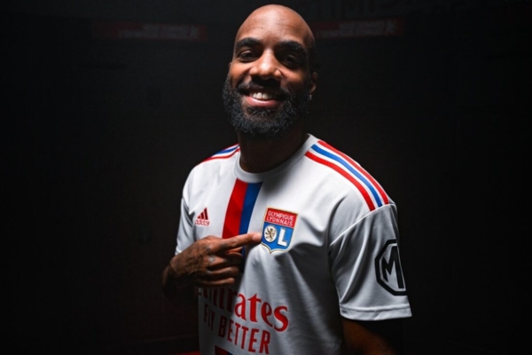 Camisa Titular Olympique Lyon Adidas 2022/23: Branca com faixa vermelha e azul, listras nos ombros, gola redonda vermelha e escudo Lyon - Homenagem à 'Era Juninho Pernambucano'.