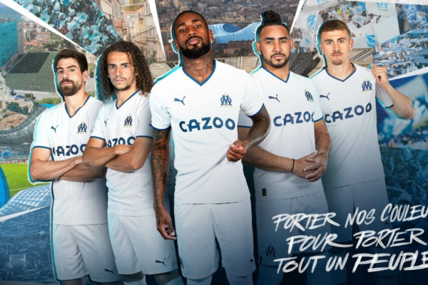 Camisa titular do Olympique de Marseille 2022/23 em branco e azul royal, gola V, punhos em azul escuro. Detalhes em embossing e faixas verticais. Logos PUMA e escudo Marseille.