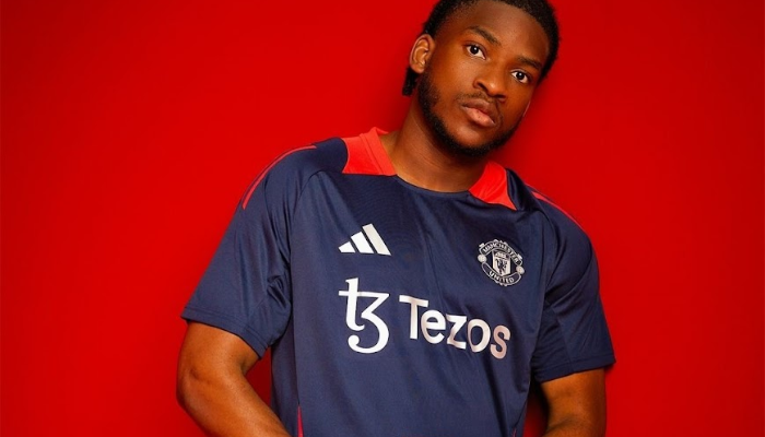 Camisa de treino oficial do Manchester United para a temporada 2024-2025, produzida pela Adidas. Apresenta design moderno com as cores azul marinho e laranja, tecido tecnológico AEROREADY para máximo conforto, e detalhes em prata metálica no brasão do clube e logo da Adidas. Ideal para treinos intensos.