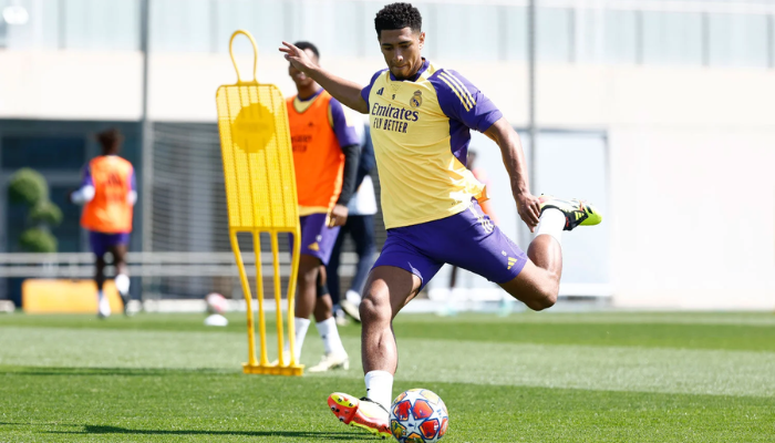 Camisa de treino oficial do Real Madrid para a temporada 2023-2024. A camisa apresenta um design moderno na cor amarela com detalhes em azul arroxeado nos logos e aplicações. A peça é confeccionada com materiais respiráveis e leves, garantindo conforto e liberdade de movimento durante os treinos.