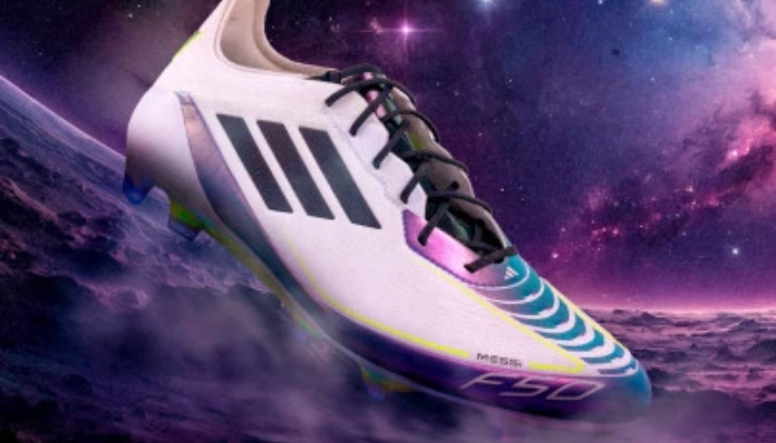 Chuteira Adidas F50 Elite FG Messi Triunfo Estelar nas cores branca, preta e roxa, com design moderno e aerodinâmico. A parte superior é feita de material sintético leve, com tecnologia SprintWeb para melhor controle da bola, além de uma sola firme com travas ideais para campos de grama natural. Perfeita para alta velocidade e desempenho.