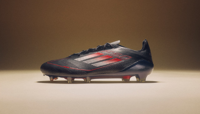 Chuteira adidas F50 Elite FG Stealth Victory na cor preta, vermelha e cinza, com design aerodinâmico e tecnologia Sprintframe 360 para aceleração máxima. Cabedal Fibertouch leve, textura Sprintweb 3D para melhor controle de bola e ajuste Compression Fit Tunnel Tongue. Modelo profissional para gramado firme, usado por estrelas como Messi e Salah.