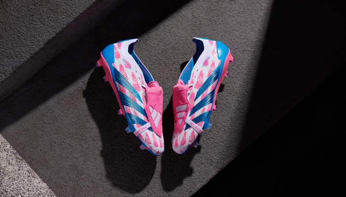 Chuteira de futebol Adidas Predator 24 em cor branca com detalhes em rosa e azul. Apresenta tecnologia Hybridskin 2.0 para melhor toque na bola, Strikeskin fins para precisão nos chutes e sola Controlframe 2.0 para estabilidade. Possui língua dobrável acolchoada e é feita com 20% de materiais reciclados.