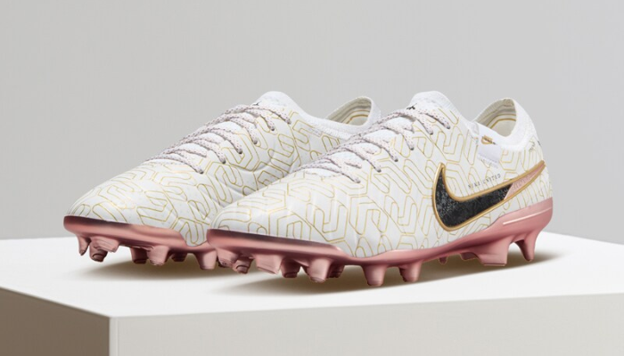 Chuteira Nike Air Zoom Mercurial Vapor 15 Elite FG United Golden em branco com detalhes dourados. A parte superior Flyknit entrelaçada oferece contato excepcional com a bola, enquanto a tecnologia ACC garante aderência ideal em todas as condições. O forro interno envolve o pé com firmeza, o amortecimento no calcanhar proporciona conforto e a palmilha antiderrapante evita o deslizamento.