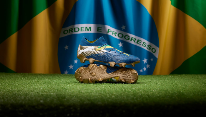 Chuteira Puma Future 7 Ultimate FG/AG Neymar Jr BNA em azul marinho, amarelo e dourado, inspirada no estilo de jogo de Neymar Jr., com tecnologias como PWRTAPE para suporte e ajuste adaptável, FUZIONFIT360 para flexibilidade e conforto