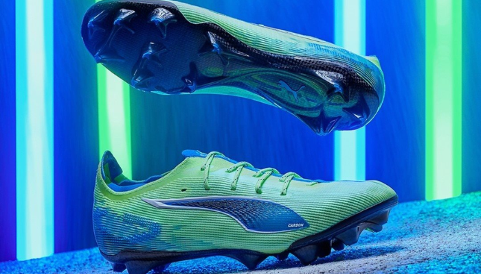 Chuteira de campo Puma Ultra 5 Ultimate FG Lights Out em verde, azul e cinza, com design vibrante, base de cor "Fizzy Apple", sistema SPEEDSYSTEM para maior aceleração, travas FastTrax para tração otimizada, suporte PWRTAPE SQD para estabilidade, palmilha NanoGrip e amortecimento OrthoLite no calcanhar, feita com materiais reciclados.