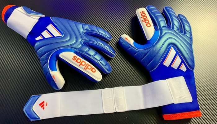 Luva de Goleiro Adidas Copa Pro Marinerush nas cores azul, branca e laranja. Feitas com poliéster reciclado, oferecem ajuste perfeito, aderência superior com URG 2.0 e conforto máximo. Ideais para treino ou partida, possuem design sustentável