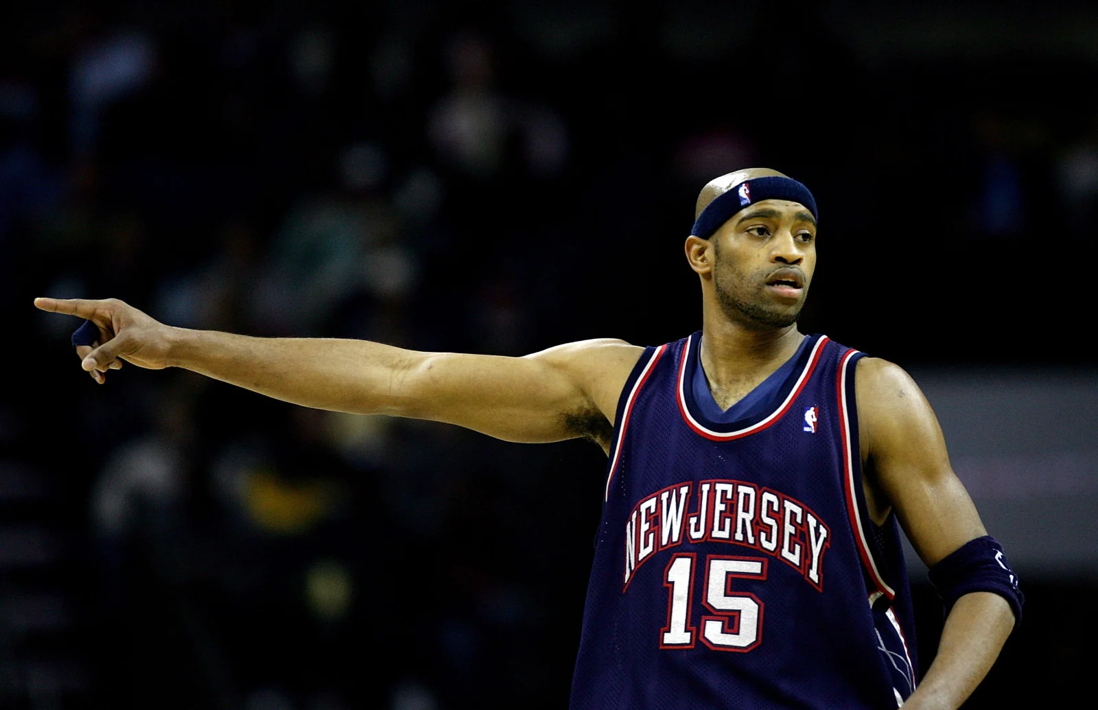 Regata reserva New Jersey Nets 2006-2007 da Mitchell & Ness, apresentando o design clássico da equipe usado por Vince Carter durante a temporada. A imagem mostra a parte frontal da regata, com o logo dos Nets em destaque nas cores azul marinho, branco e vermelho.