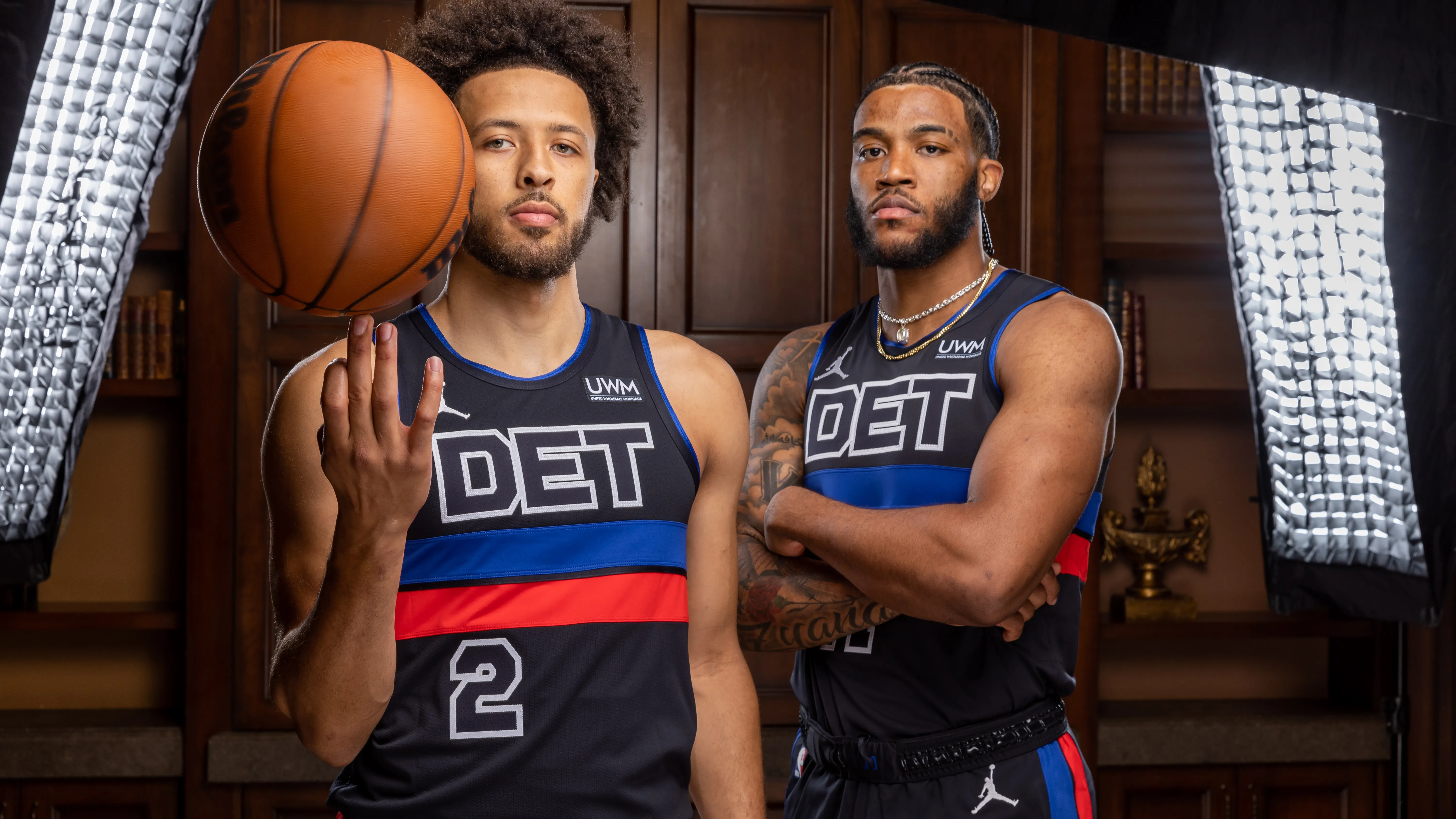 Imagem da Regata Statement Edition Detroit Pistons Jordan 2022/24 em preto, azul royal, vermelho e branco. Destaque para as listras horizontais e o emblema 'DET' em letras recortadas brancas, representando a intensidade e estilo do uniforme | Tevo Sports