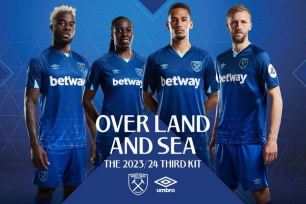 Terceira Camisa West Ham Umbro 2023/24 em azul marinho e branco, destacando padrão de treliça, gola V e detalhes em azul celeste, com escudo monocromático e logos da Umbro. Patrocínios Betway e JD em branco. Inspirada no London Stadium.