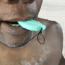 Homem negro com barba branca por fazer com um mordedor em formato de folha na boca