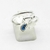 ANILLO CRUZADO CON DIJES OJITOS CORAZON ACERO QUIRURGICO PLATEADO